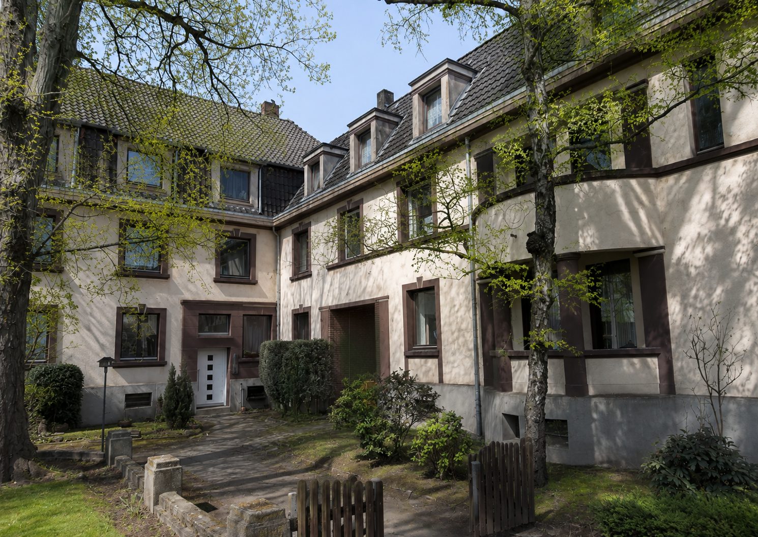 Wohnanlage mit begrüntem Innenhof und Mansarddächern